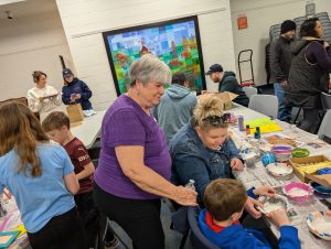 Image of Nancy Dryden assisting children in making bowl art Kiwanis Kraft Days May 2nd, 2026 | Kiwnais Club of Bradford