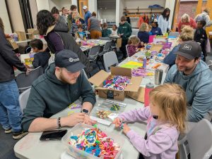 Nick Ward heling a child make a bracelet while her father watches | Kiwanis Kraft Days | Kiwanis Club of Bradford