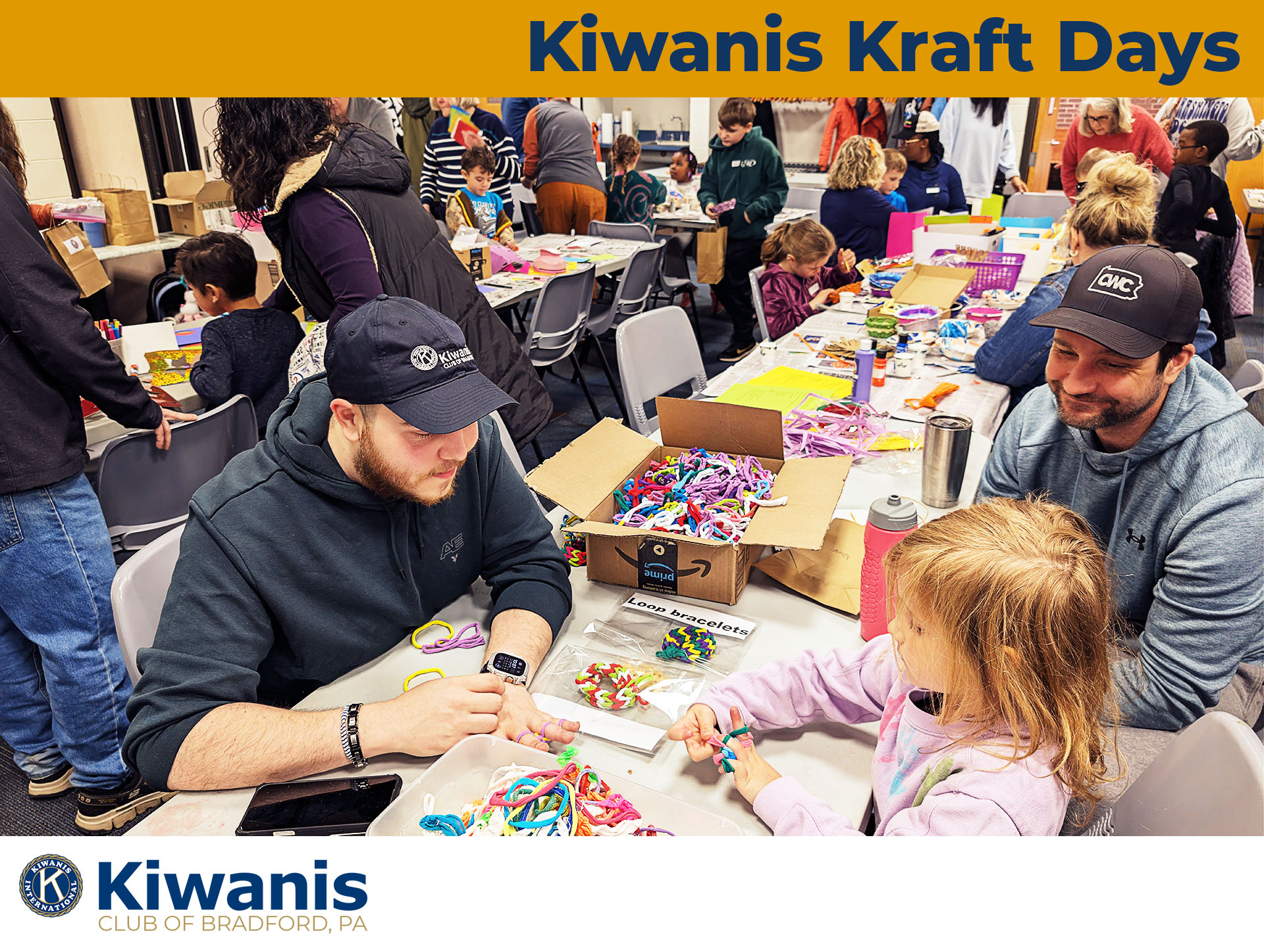 Image of Nick Ward working with a family to teach them how to make bracelets surrounded by other patrons also making crafts at Kiwanis Kraft Days, May 2nd, 2026 | Kiwanis Club of Bradford